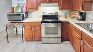 A kitchen with wooden cabinets, a microwave, a stove, and a ceiling fan. - 3-bedroom house in amazing Orlando with AC and fitness room-BEACH STYLE BUNGALOW (Orlando)