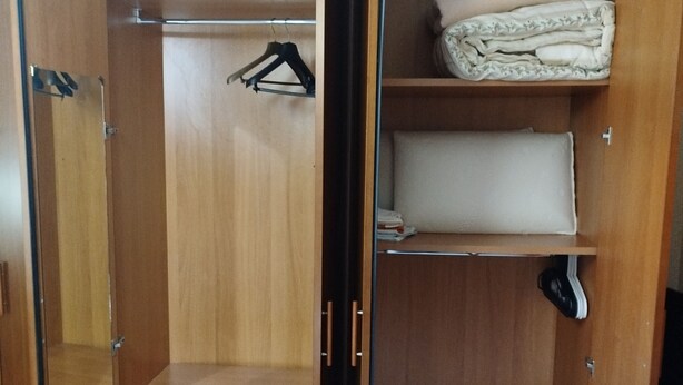 Un armario de madera con varios compartimentos, incluyendo espacio para colgar y estantes.