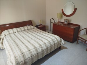 A bedroom with a bed, a dresser, a chair, a nightstand, a lamp, and a mirror. - Convent Palace (Barrafranca)