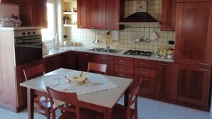 Una cocina con armarios de madera, una estufa a gas, un lavabo y una mesa de comedor con sillas.