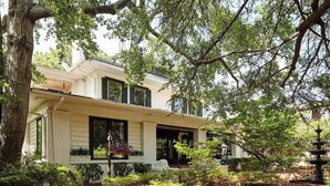 A two-story house with a covered porch, surrounded by trees and a garden. - Apt2@EdenBrae - Walkable Southern Gothic Mansion (Birmingham)