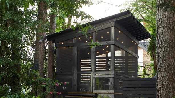 A rustic wooden cabin with a porch, surrounded by lush greenery and trees. - Apt2@EdenBrae - Walkable Southern Gothic Mansion (Birmingham)
