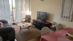 A living room with a sofa, a round coffee table, a television, and a dining area with a table and chairs. - Providencia 2BR 2BA Apt + Private Parking (Providencia)