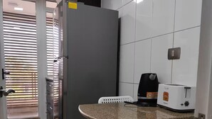 A kitchen with a refrigerator, a toaster, and a table with chairs. - Providencia 2BR 2BA Apt + Private Parking (Providencia)