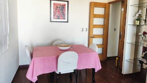 A dining area with a table covered in a pink tablecloth, white chairs, a wooden door, and a framed picture on the wall. - Providencia 2BR 2BA Apt + Private Parking (Providencia)