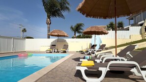 Ein Pool mit Liegestühlen und Reetdachschirmen.