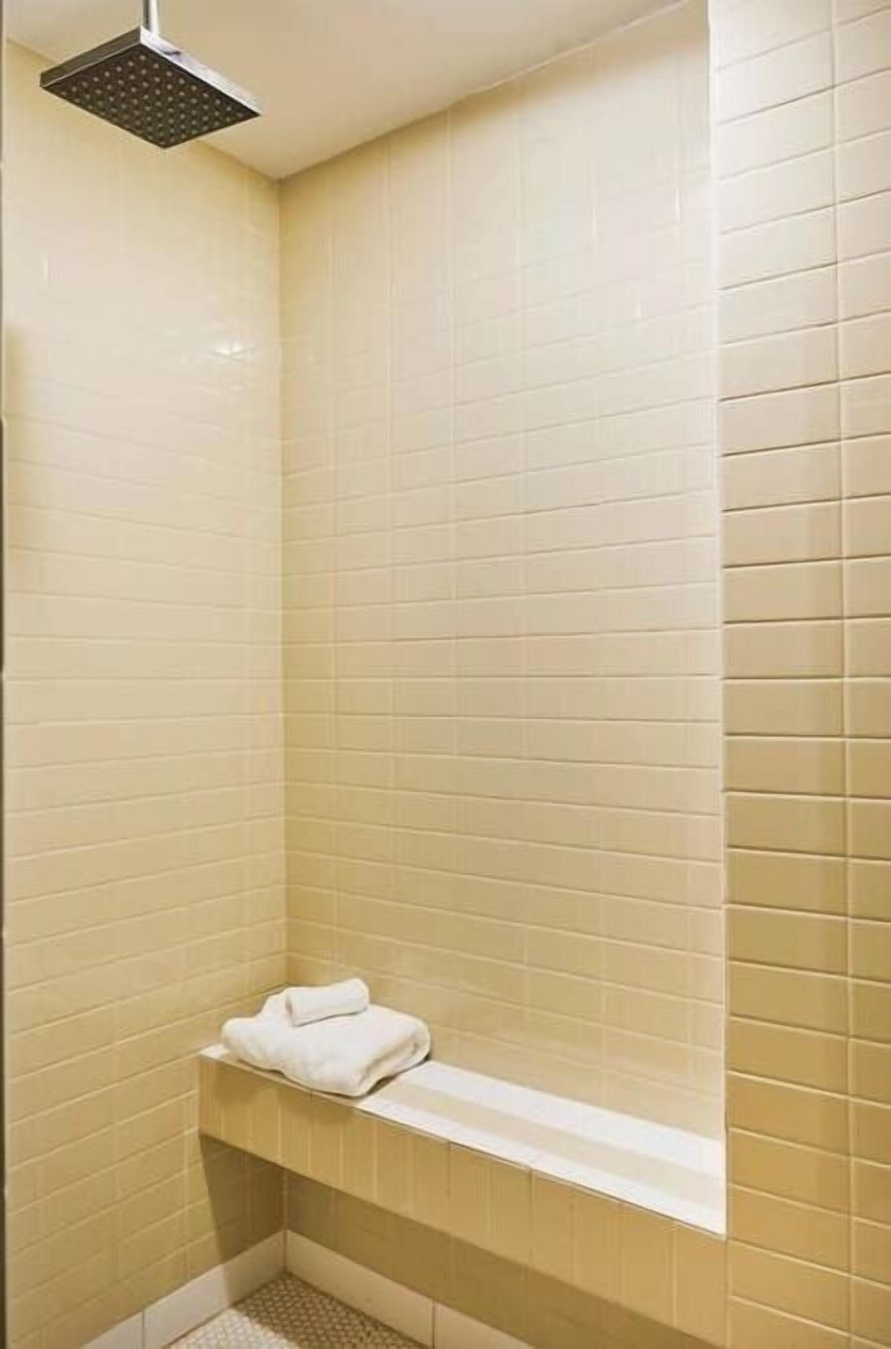 A small, tiled shower area with a bench and a towel.