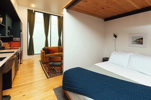 Un dormitorio con cama, sofá, mesa de comedor y zona de cocina.