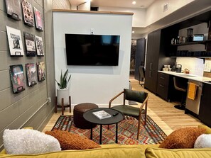 A modern living room with a flat-screen TV, a coffee table, a sofa, and a patterned rug.