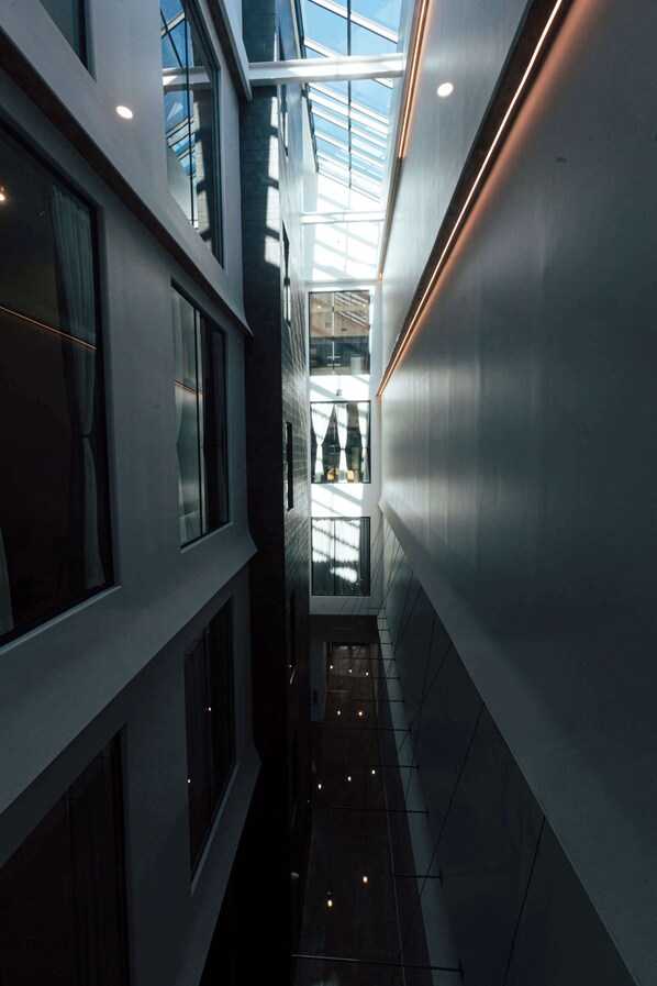 A modern building with a glass atrium, a narrow corridor, and a staircase.