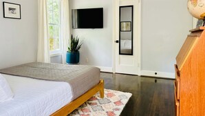 Ein Schlafzimmer mit einem Bett, einem Blumentopf, einem Fernseher, einer Tür und einem Globus.