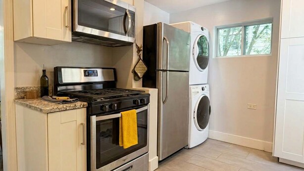 Eine moderne Küche mit Edelstahlgeräten, einem Backofen, einer Mikrowelle und einer Waschmaschine.