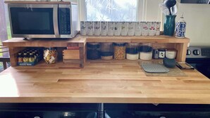 A kitchen counter with a microwave, beverage mixers, and various containers. - Victorian on Garden: Best Location in Town (Bellingham)