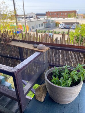 A balcony with a woven fence, a potted plant, and a small birdhouse. - Victorian on Garden: Best Location in Town (Bellingham)