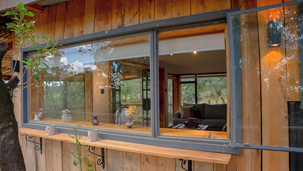 A wooden cabin with large windows, a wooden bench, and a view of the interior.