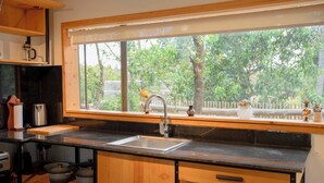 A kitchen with a large window, wooden cabinets, a sink, and various kitchen appliances.