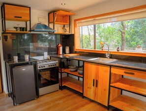 A compact kitchen with a gas stove, oven, and a small refrigerator. - Tree House cabin nestled in Turbo ,Eldoret perfect for a cozy getaway (Eldoret)