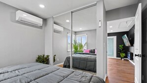 Ein modernes Schlafzimmer mit einem großen Bett, einer Schiebetür zum Kleiderschrank und Blick auf einen Balkon.
