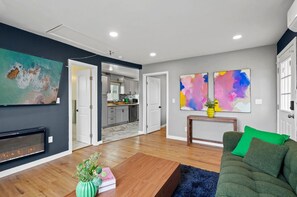 Ein modernes Wohnzimmer mit Kamin, einem grünen Sofa und abstrakten Bildern an der Wand.