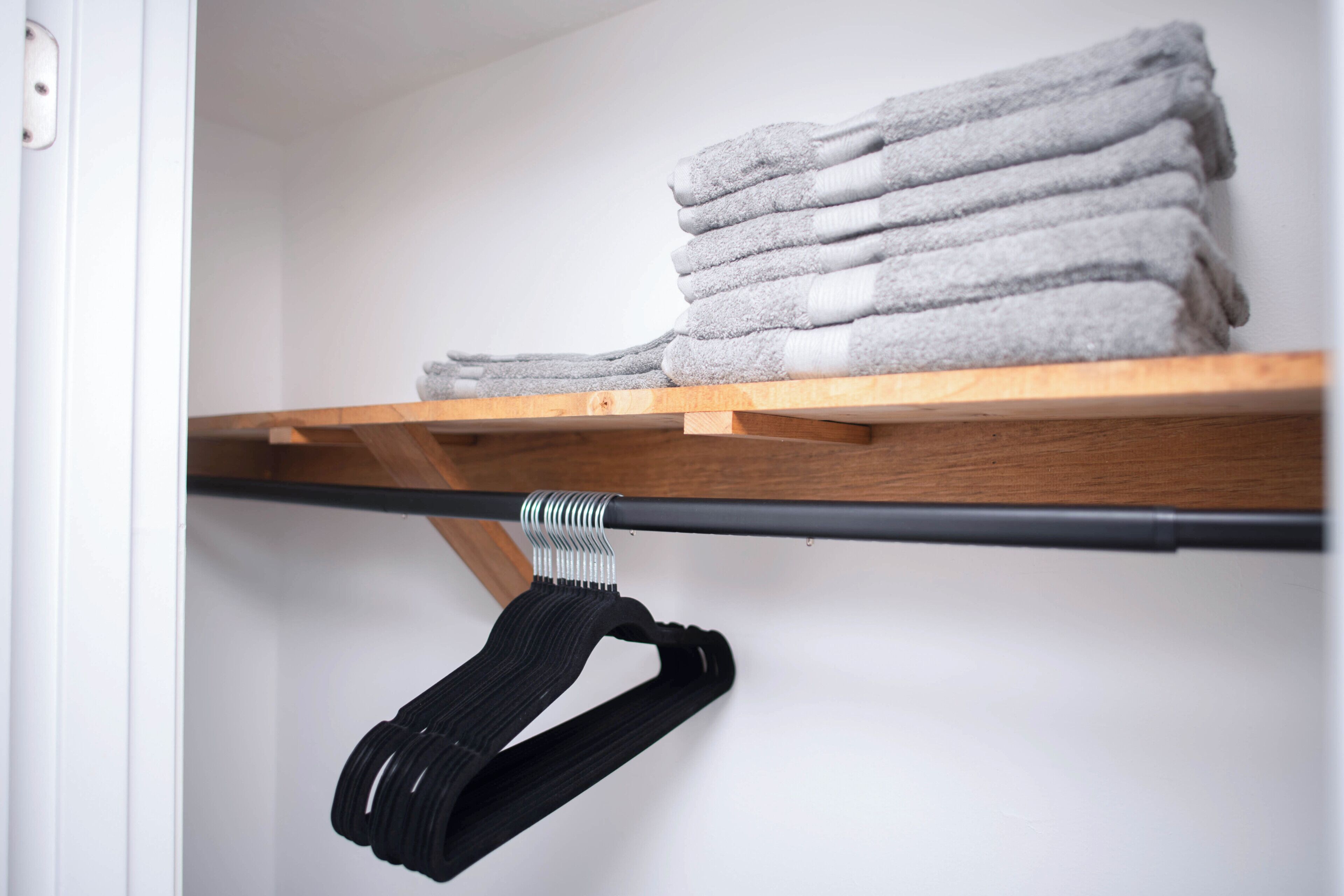 A neatly organized shelf with folded towels and a black bag hanging.