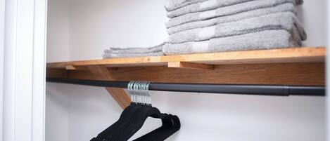 A neatly organized shelf with folded towels and a black bag hanging.