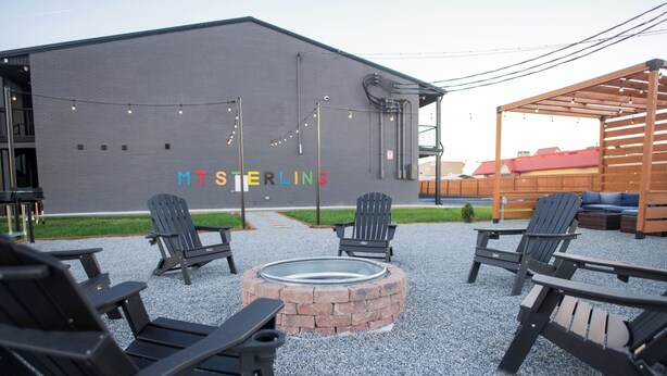 Un espace extérieur aménagé avec des chaises Adirondack, un foyer et un bâtiment portant l’inscription « MTS STERLING ».