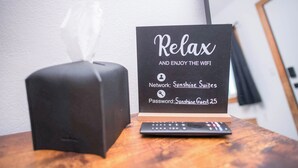 Une boîte de mouchoirs, un panneau indiquant les informations de connexion Wi-Fi et une télécommande posées sur une surface en bois.