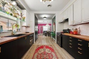 Une cuisine moderne avec des meubles noirs, un plan de travail en bois et un tapis rouge à motifs.