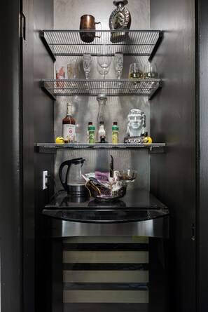 Une cuisine équipée d’une machine à café, d’une bouilloire et d’une bouteille de whisky posée sur le plan de travail.
