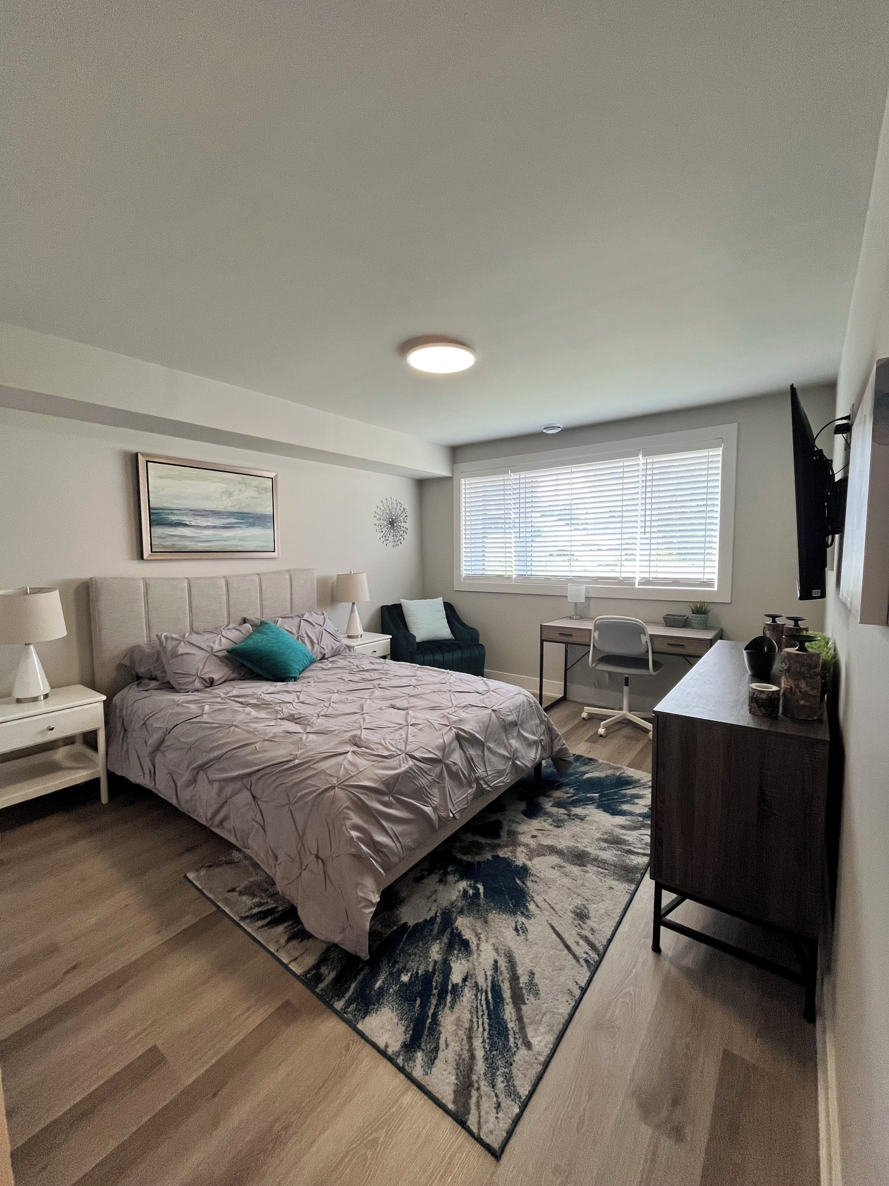 A bedroom with a bed, bedside tables, a desk, and a chair.