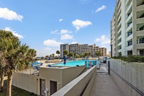 A swimming pool with lounge chairs and palm trees, surrounded by a high-rise building. - The Hudson Resort On The Gulf (Hudson)