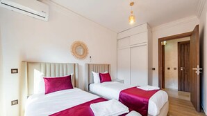Een hotelkamer met twee bedden, een spiegel, een kledingkast en een deur.