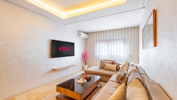 Een moderne woonkamer met een bank, een salontafel en een televisie waarop 'NETFLIX' staat.