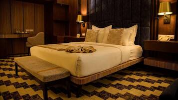 Een hotelkamer met een groot bed, nachtkastjes, een stoel en een receptiebalie.