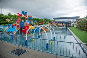 Parque acuático con toboganes, piscina y un edificio al fondo.