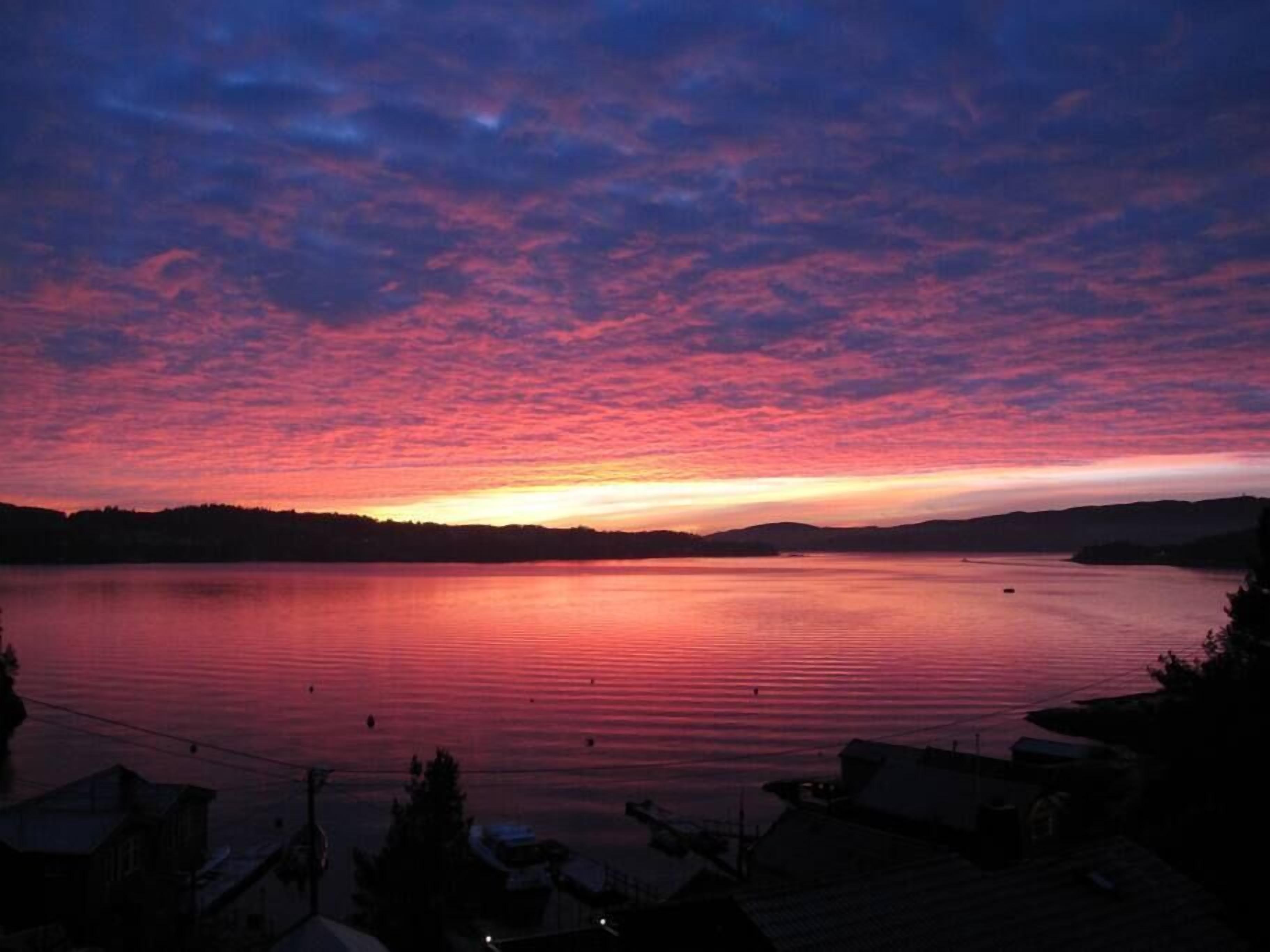 Un lac au coucher du soleil, sous un ciel dégagé.