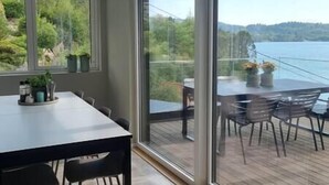 Un espace repas comprenant une table et des chaises, de grandes fenêtres et une vue sur un lac.