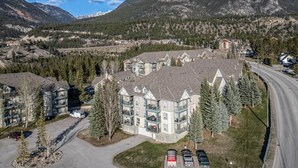 Un quartier résidentiel avec un grand immeuble doté de nombreux balcons, entouré d’arbres et bordé par une route.
