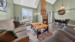 Un salon spacieux avec une cheminée, un coin repas et une vue sur l’extérieur.