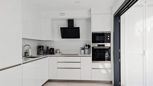 Una cocina moderna con armarios blancos, un microondas negro y un horno empotrado.