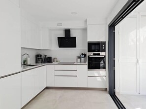 Eine moderne Küche mit weißen Schränken, einer schwarzen Mikrowelle und einem eingebauten Backofen.