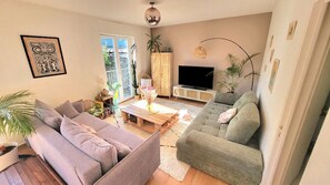 Un salon avec un canapé, un téléviseur et une table basse.