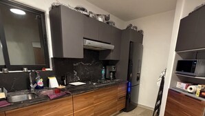 Uma cozinha moderna com bancada preta, armários de madeira e pia de aço inoxidável, e um micro-ondas.