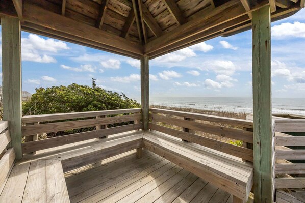 Een houten terras met uitzicht op de oceaan en het strand.