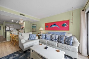 Een woonkamer met een bank, salontafel en een eethoek met stoelen en een tafel.