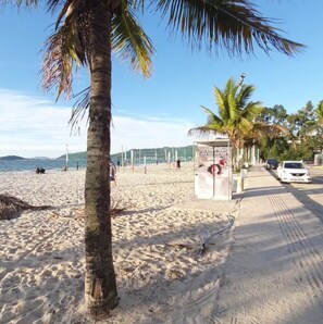 En strand med palmer, ett volleybollnät och en klar himmel.