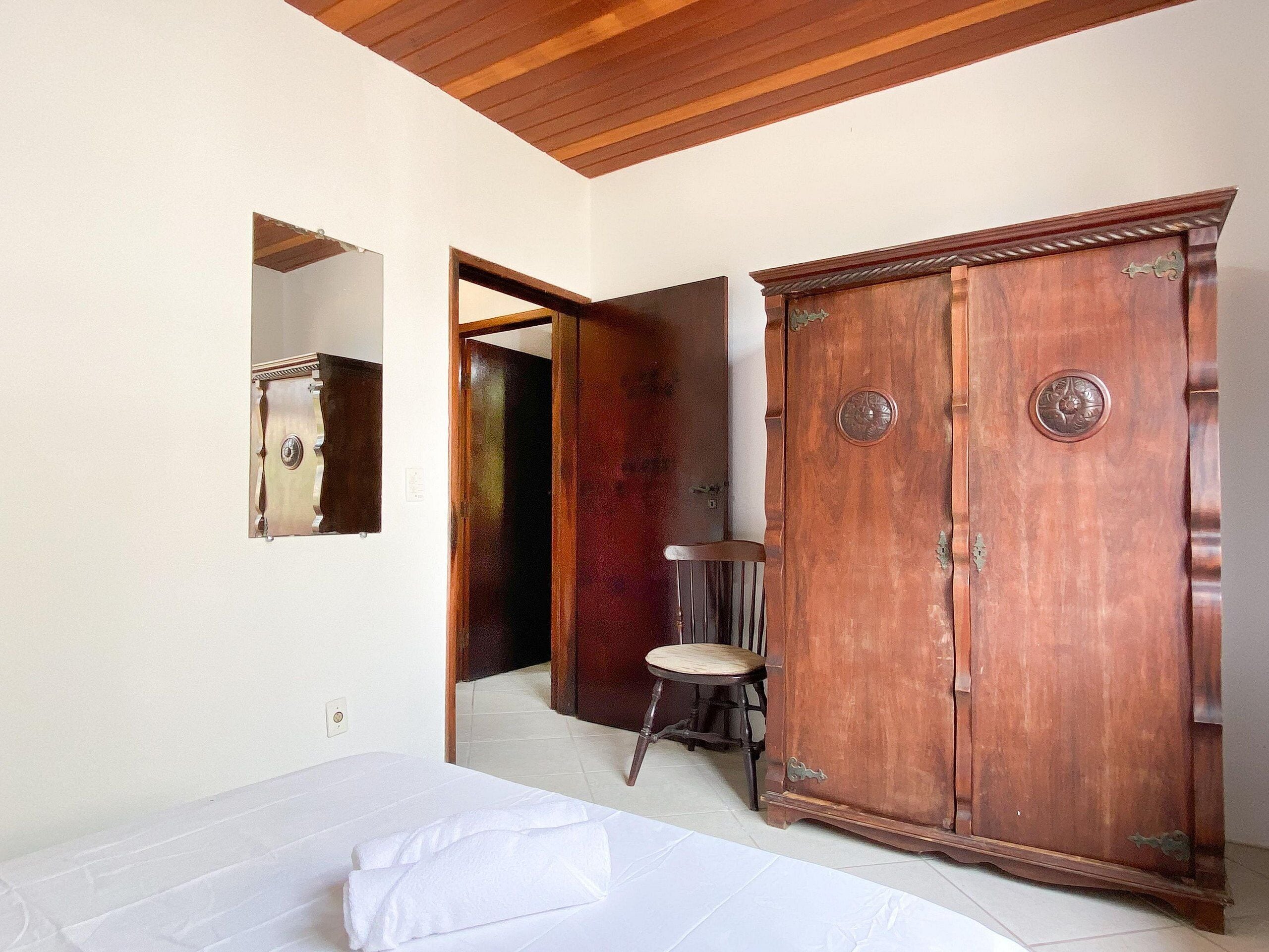 Une pièce comprenant un lit, une armoire en bois et un miroir au mur.