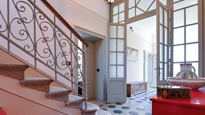 A staircase with ornate metal railings, a red cabinet, and a large decorative bowl on a red table.