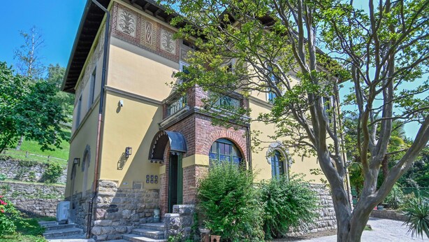 A two-story building with a stone foundation, a brick section, and a yellow facade.