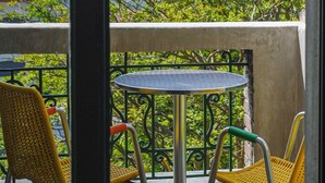 A balcony with a table and two chairs, overlooking a mountainous landscape.